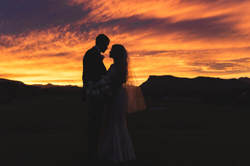 bride and groom standing infront of the sunset