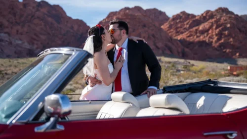 as Vegas elopement couple kissing in a red classic convertible at Red Rock Canyon